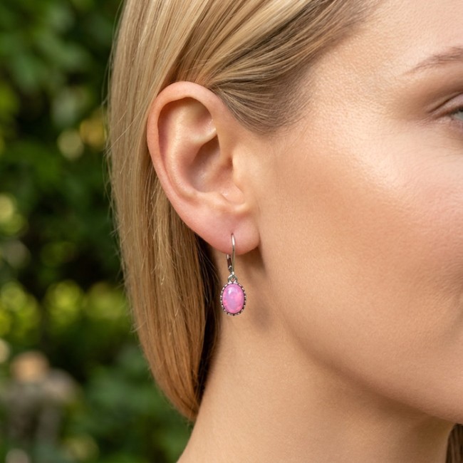 Srebrne kolczyki z różowym opalem pink fire na uchu modelki — wiszący kamień w oksydowanej oprawie, Polcarat Design